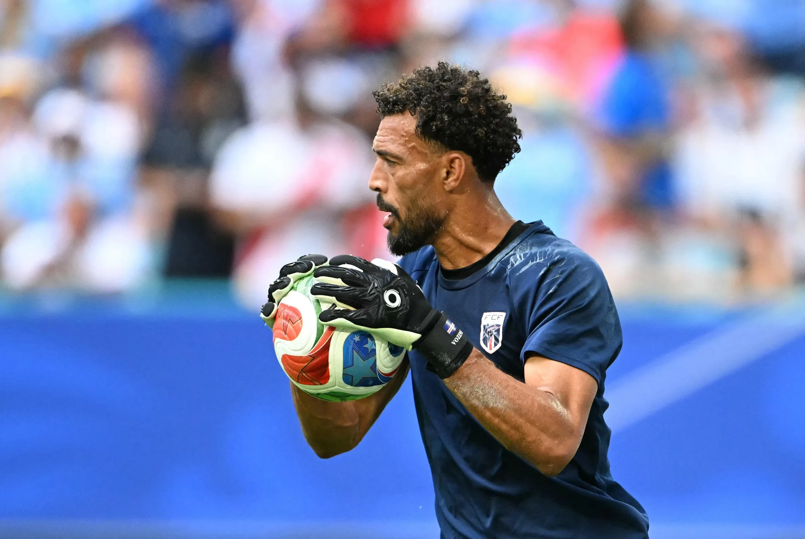 Goalkeeper Vozinha in a dark blue jersey holds a colorful ball during the warm-up
