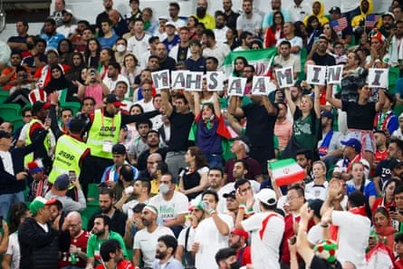Des agents de sécurité demandent aux fans de retirer une pancarte avec le nom de Mahsa Amini lors du match de groupe B de la Coupe du Monde 2022 entre l'Iran et les États-Unis