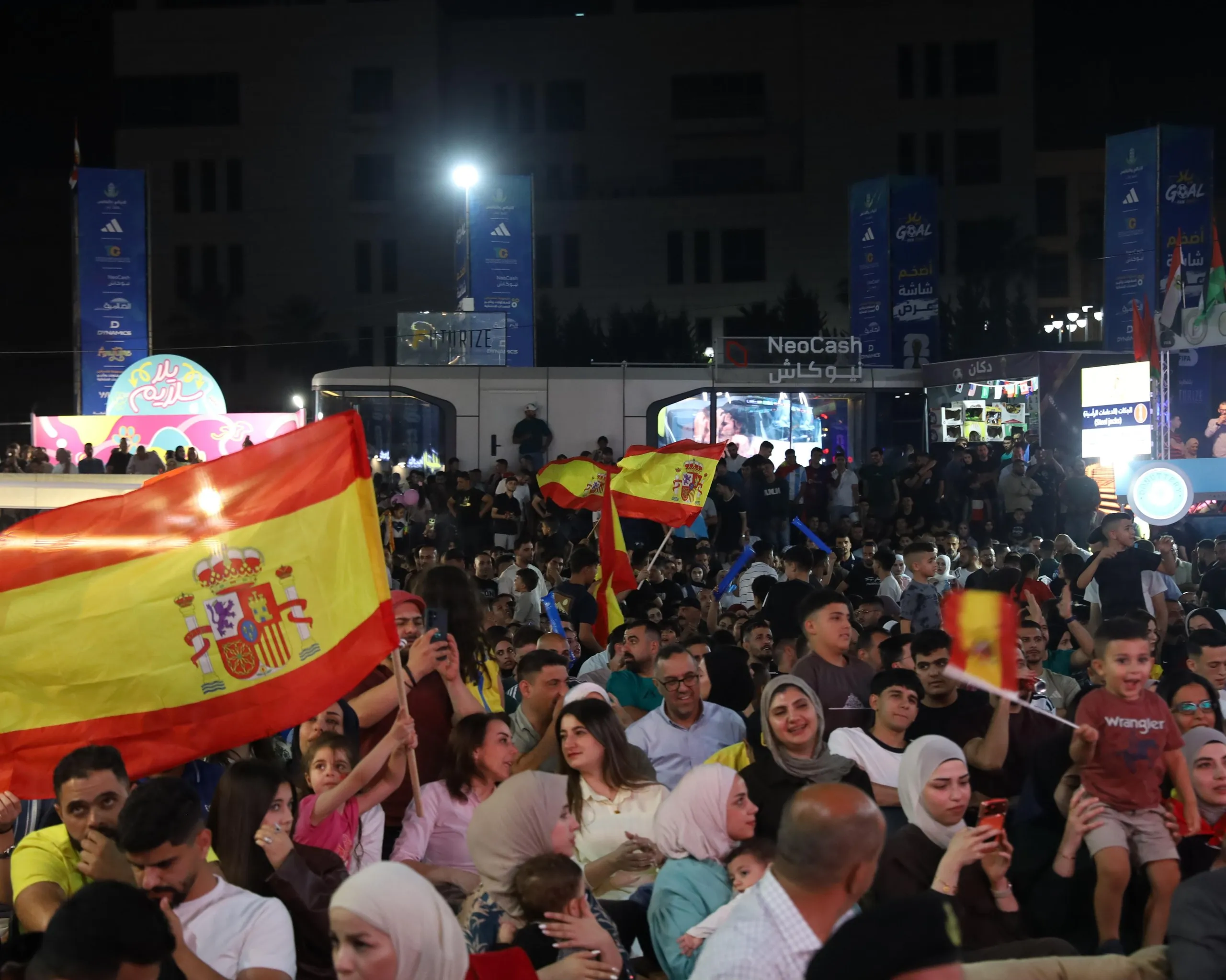 Supporters waving Spanish flags follow the match with excitement.