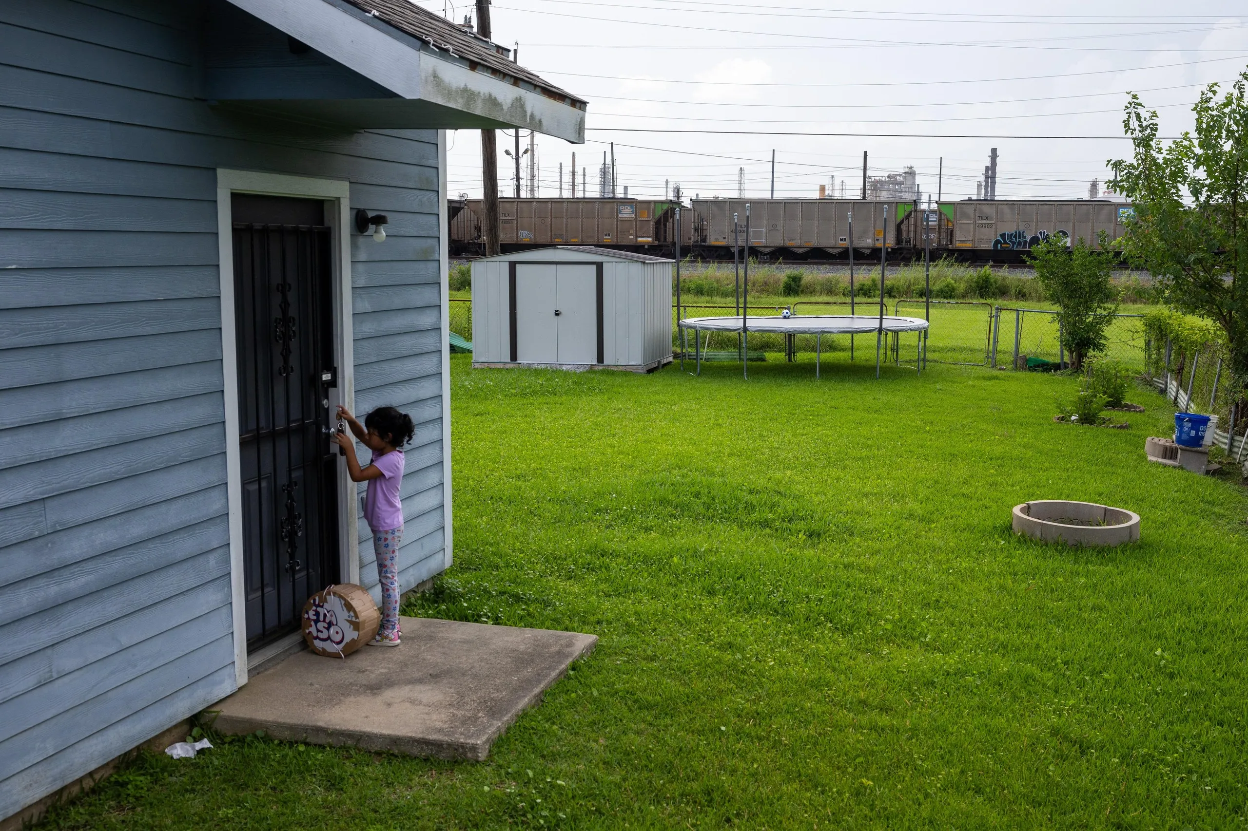 A child outside her family’s front door across the train tracks from the Motiva refinery.