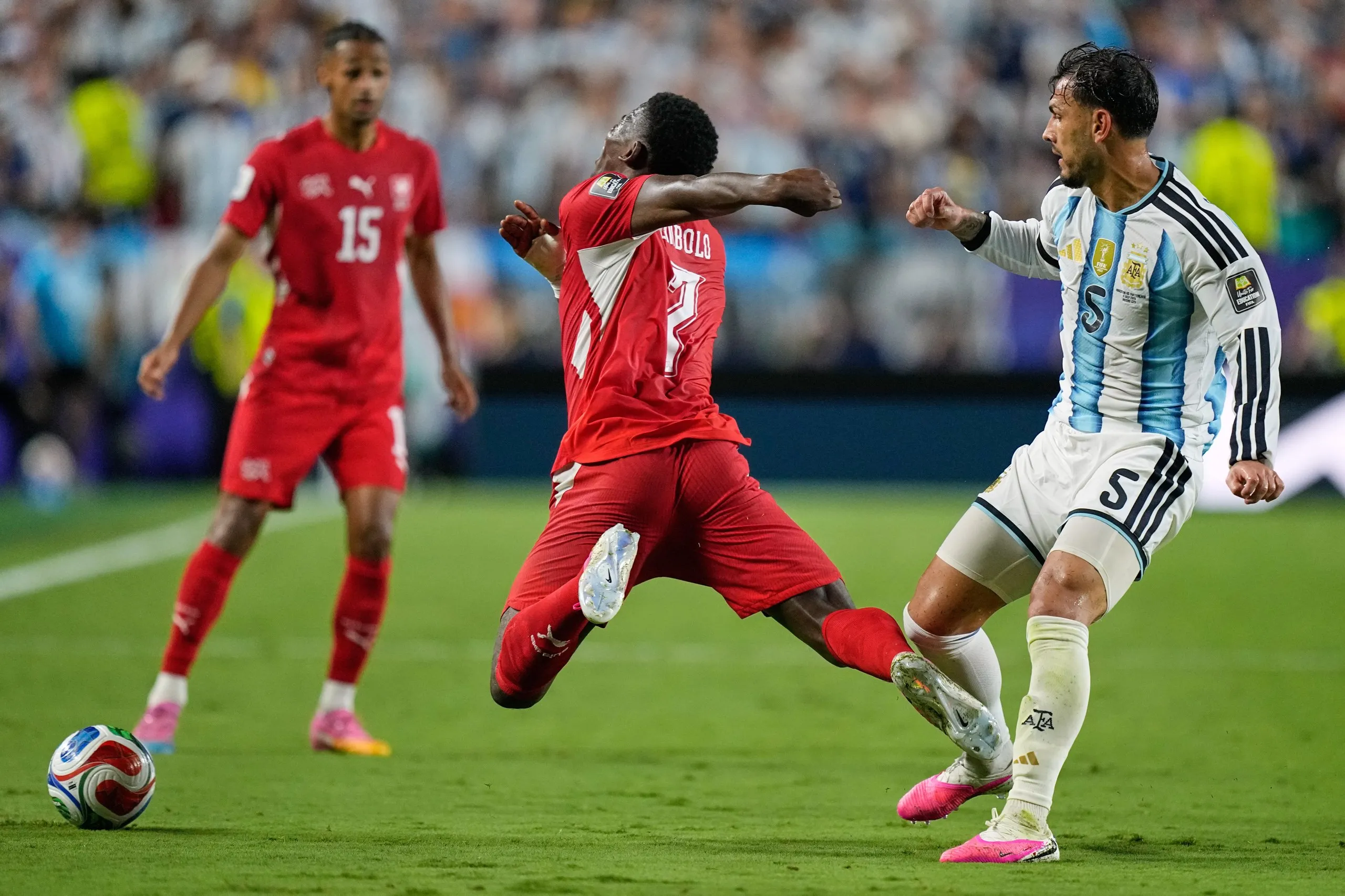Switzerland’s Breel Embolo falls to ground under pressure from Argentina’s Leandro Paredes